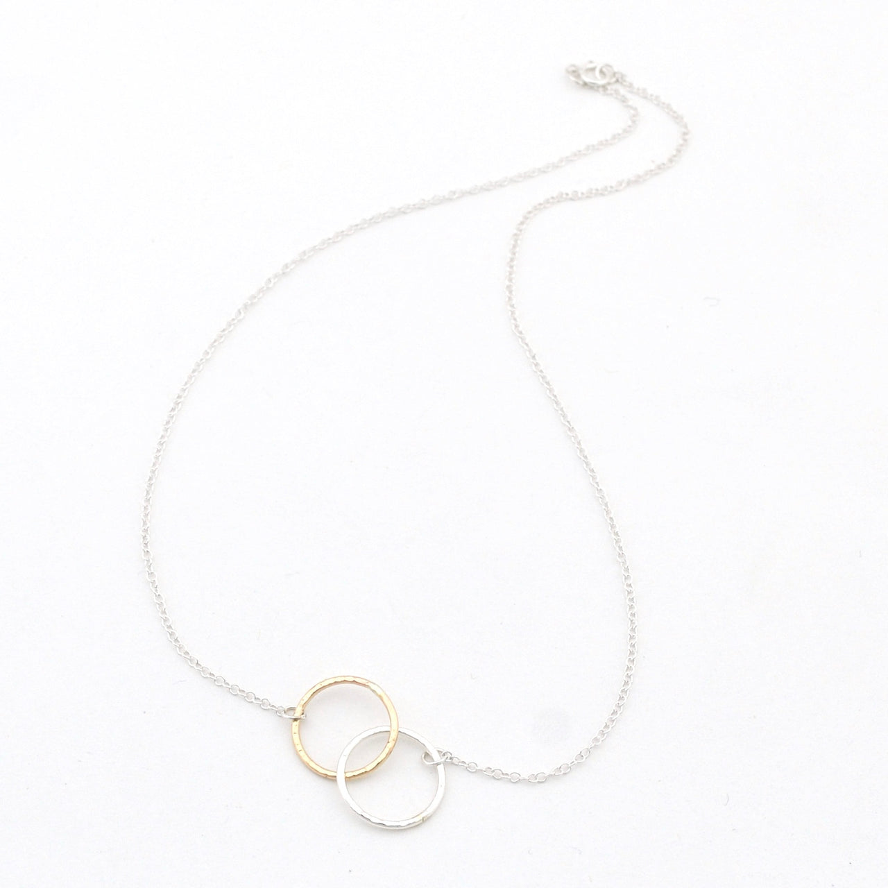 Necklace with a gold and silver circular pendant on a white background