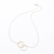 Necklace with a gold and silver circular pendant on a white background