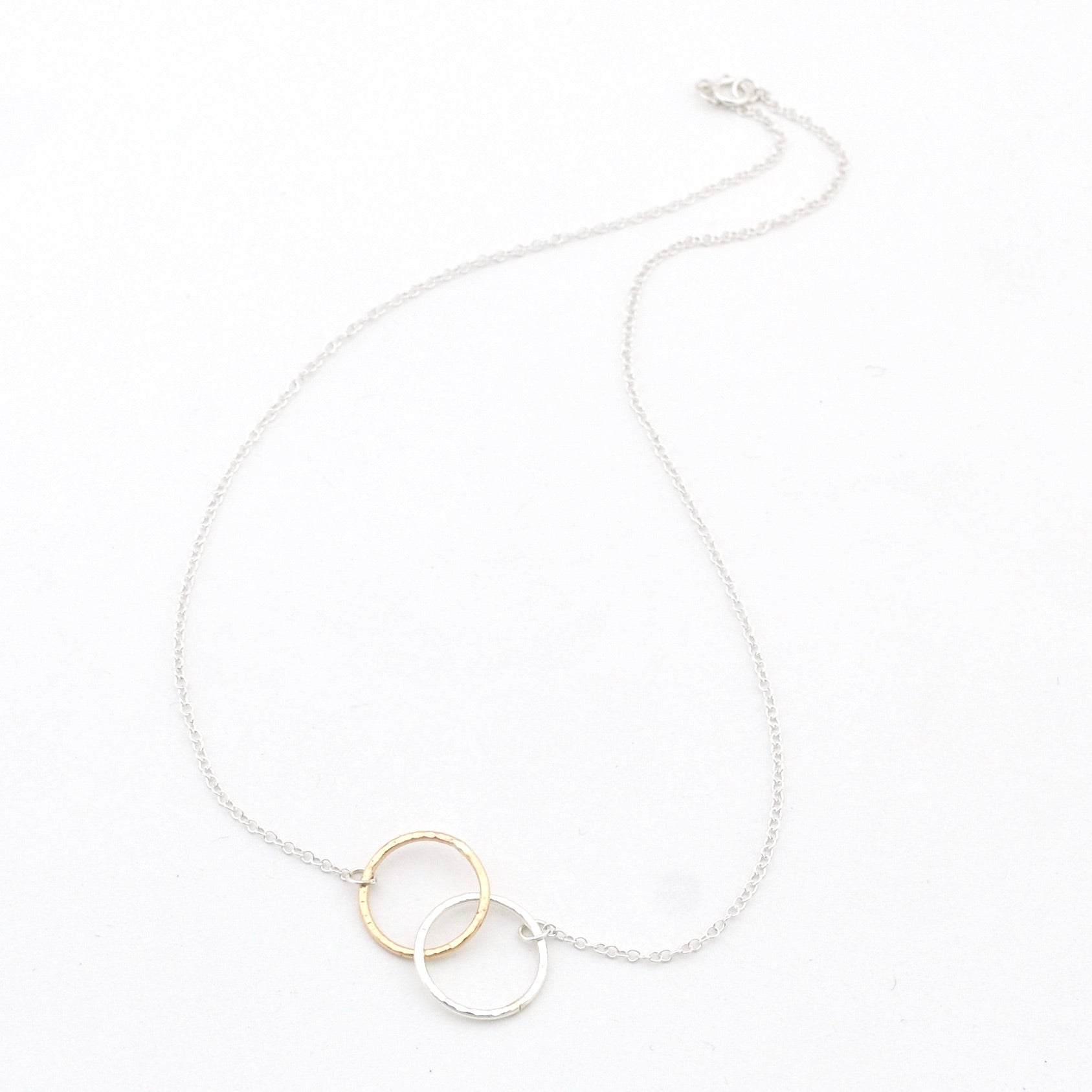 Necklace with a gold and silver circular pendant on a white background