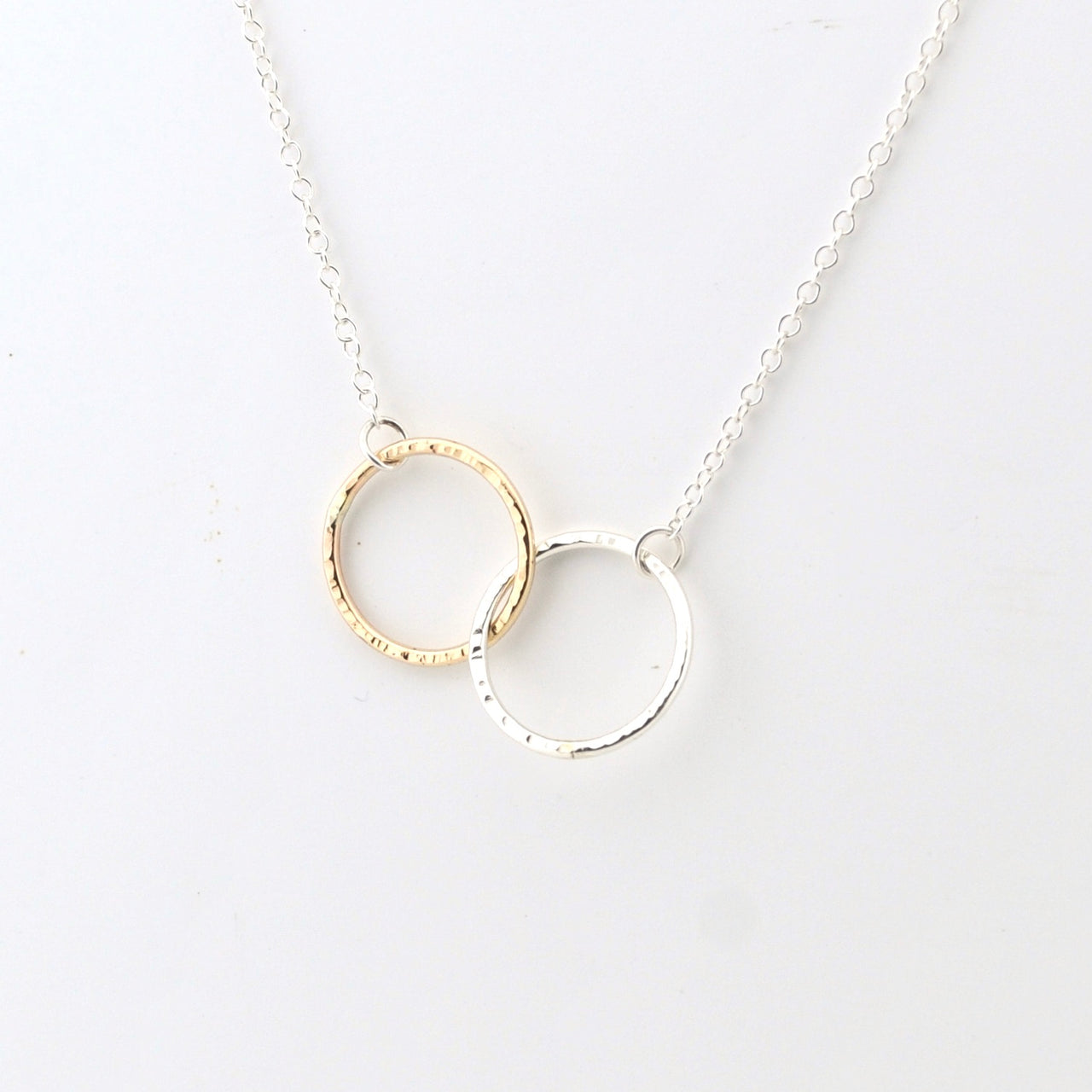Necklace with interlocking gold and silver rings on a white background