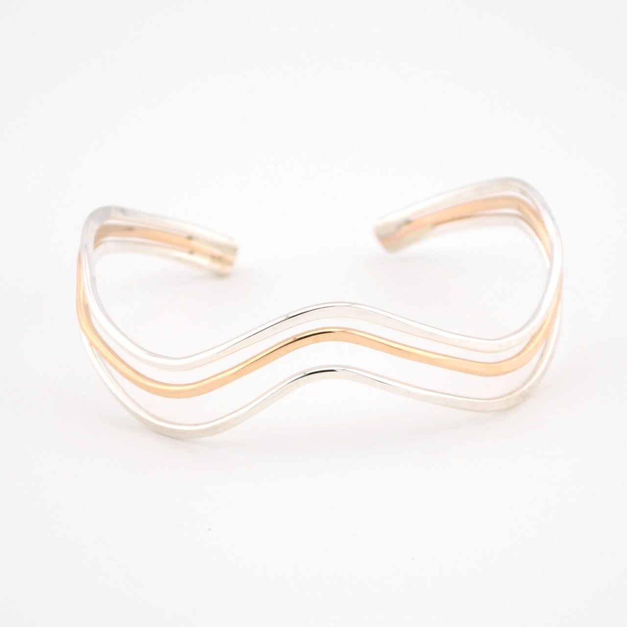 Gold and silver wave-patterned bracelet on a white background
