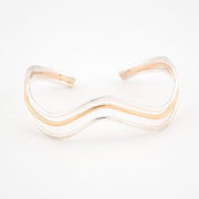 Gold and silver wave-patterned bracelet on a white background