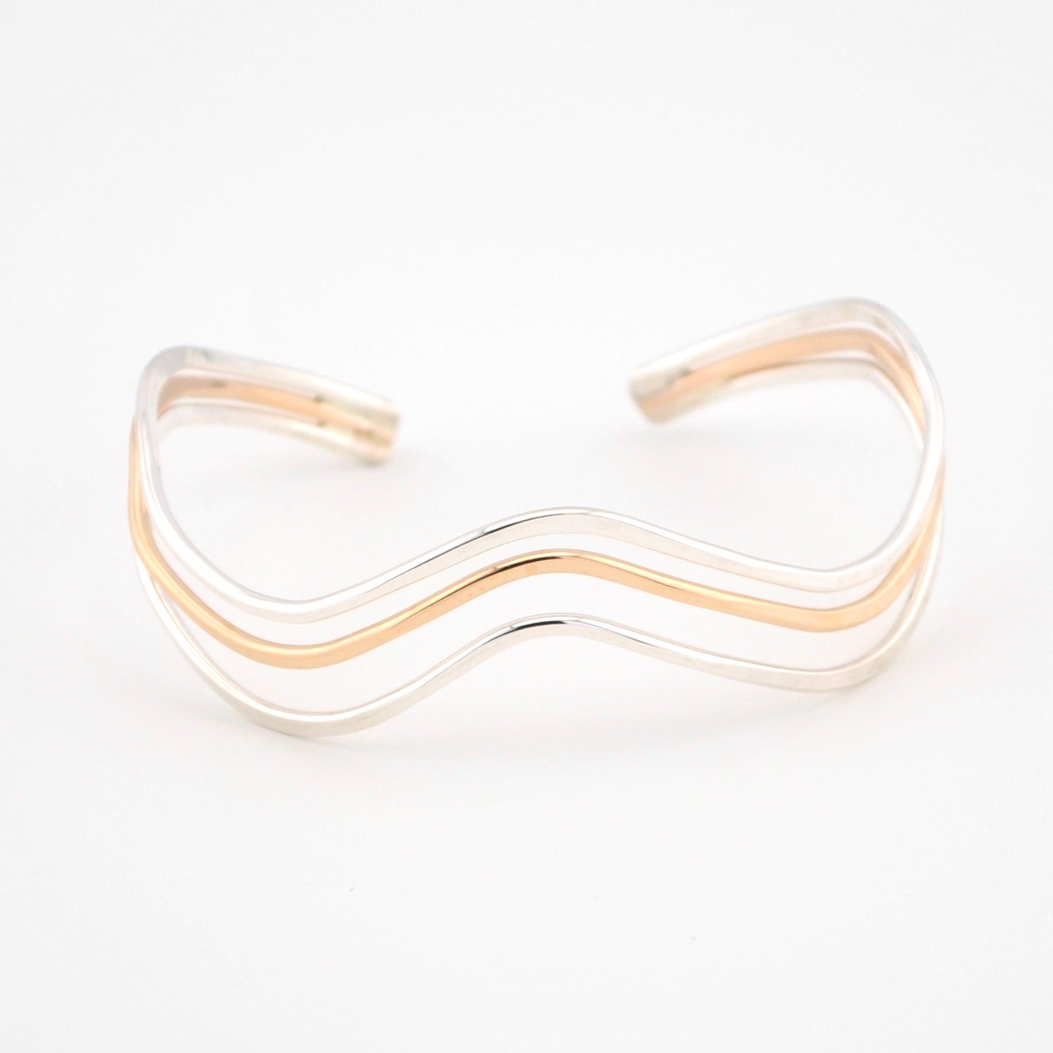 Gold and silver wave-patterned bracelet on a white background