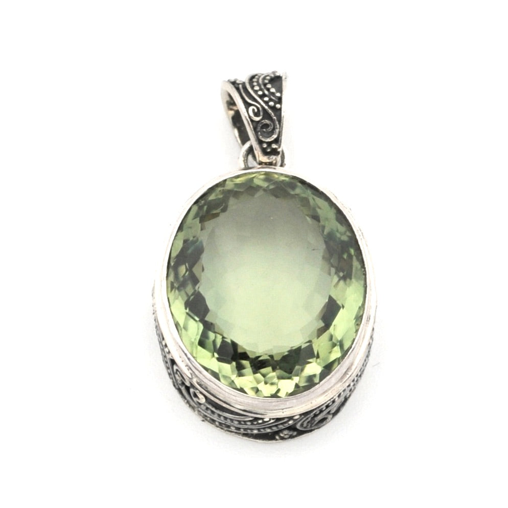 An oval-cut light green gemstone pendant set in a silver-toned metal bezel with ornate filigree detailing on the sides and bail, shown against a plain white background.