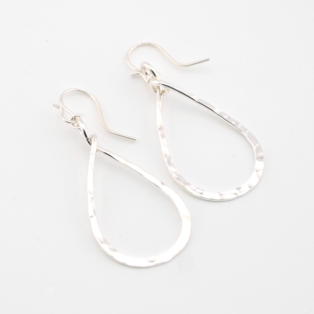 Silver teardrop earrings on a light gray background