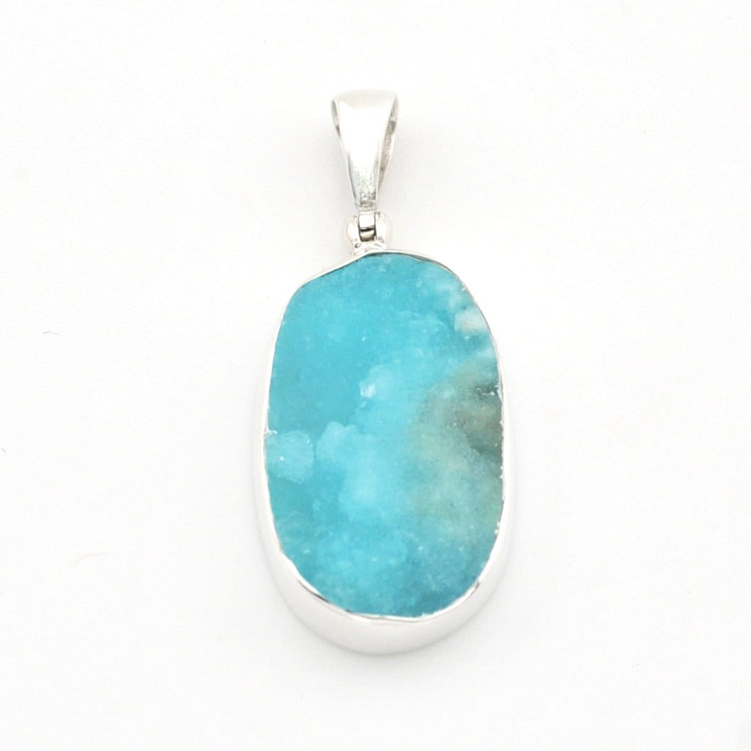 A silver pendant featuring a large, irregularly shaped turquoise-blue stone with natural white and gray marbling, set against a plain white background.
