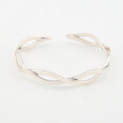 Silver bracelet with a wavy design on a white background