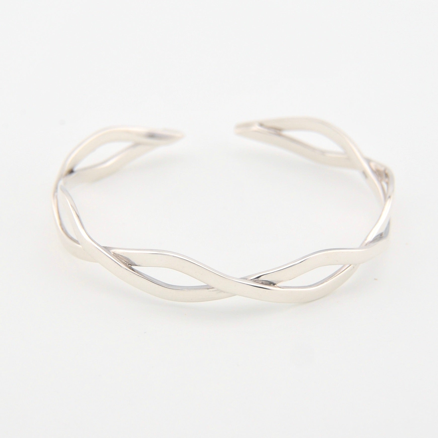Silver bracelet with a wavy design on a white background
