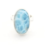 A silver ring featuring an oval-shaped light blue larimar stone with natural white veining, set against a plain white background.