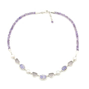 A lavender-toned beaded necklace featuring vintage porcelain, pearls and sea glass, displayed on a clean white background.