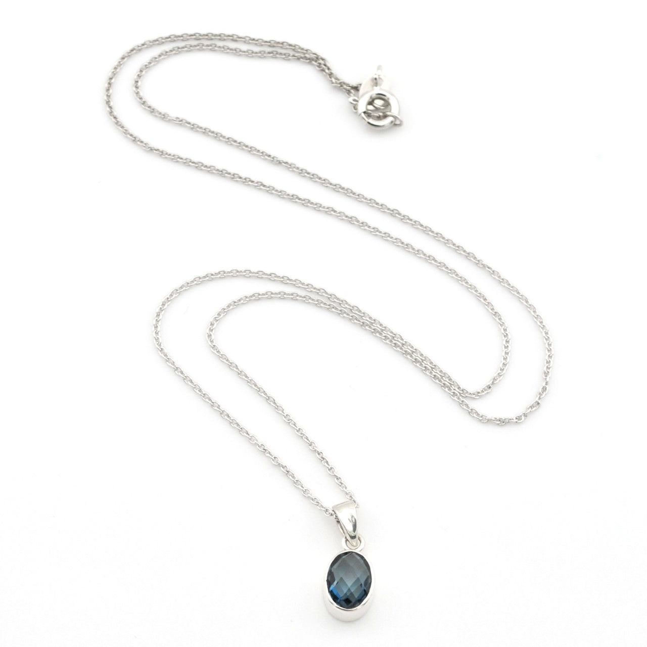 A silver chain necklace with a small oval dark blue gemstone pendant, displayed on a clean white background.