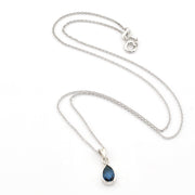 A silver chain necklace with a teardrop-shaped dark blue gemstone pendant, displayed on a clean white background.