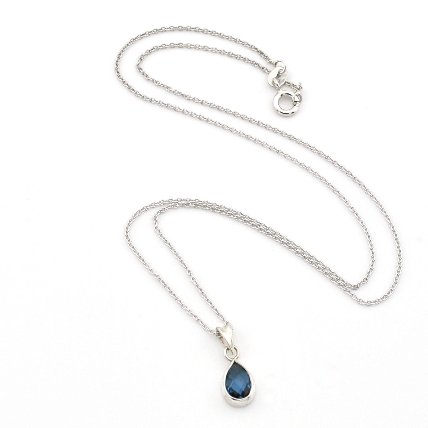 A silver chain necklace with a teardrop-shaped dark blue gemstone pendant, displayed on a clean white background.