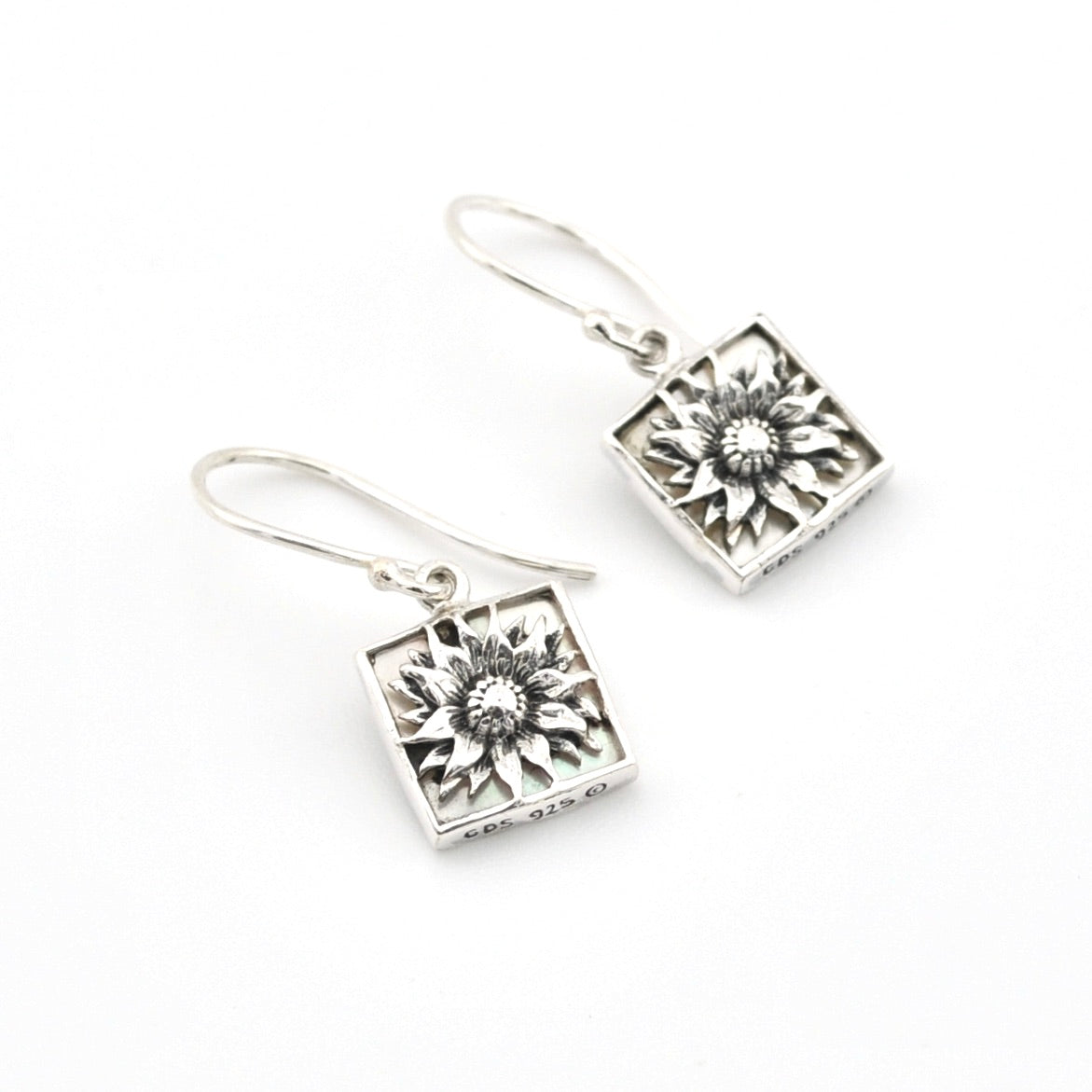 Silver square earrings with floral designs on a white background