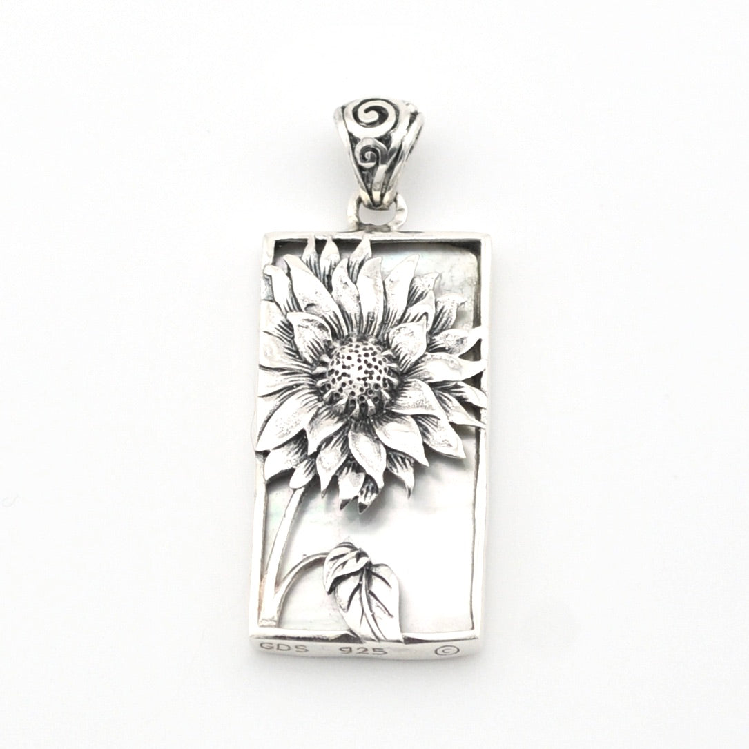 Silver pendant with sunflower design on a white background