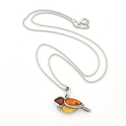 A silver chain necklace featuring a bird pendant made from two amber-colored stones, one dark reddish-brown and one golden-yellow, displayed on a clean white background.