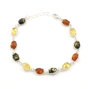 A silver link bracelet featuring oval-cut natural Baltic amber stones in yellow, orange, and dark brown-black hues, displayed on a clean white background.