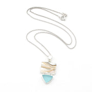 A silver chain necklace with a shell with sea glass pendant, shown open on a white background. 
