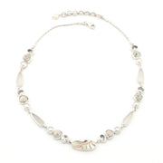 A silver-toned beaded necklace featuring a central polished nautilus shell, oval gems, and smaller round shell and pearls, displayed on a clean white background.