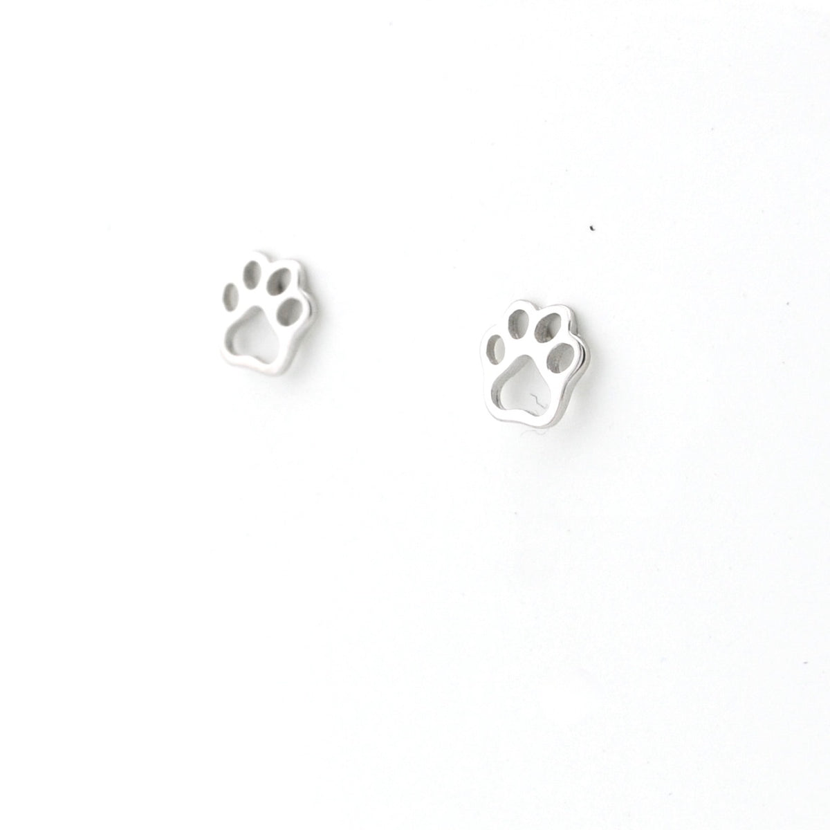Pair of silver paw print earrings on a white background