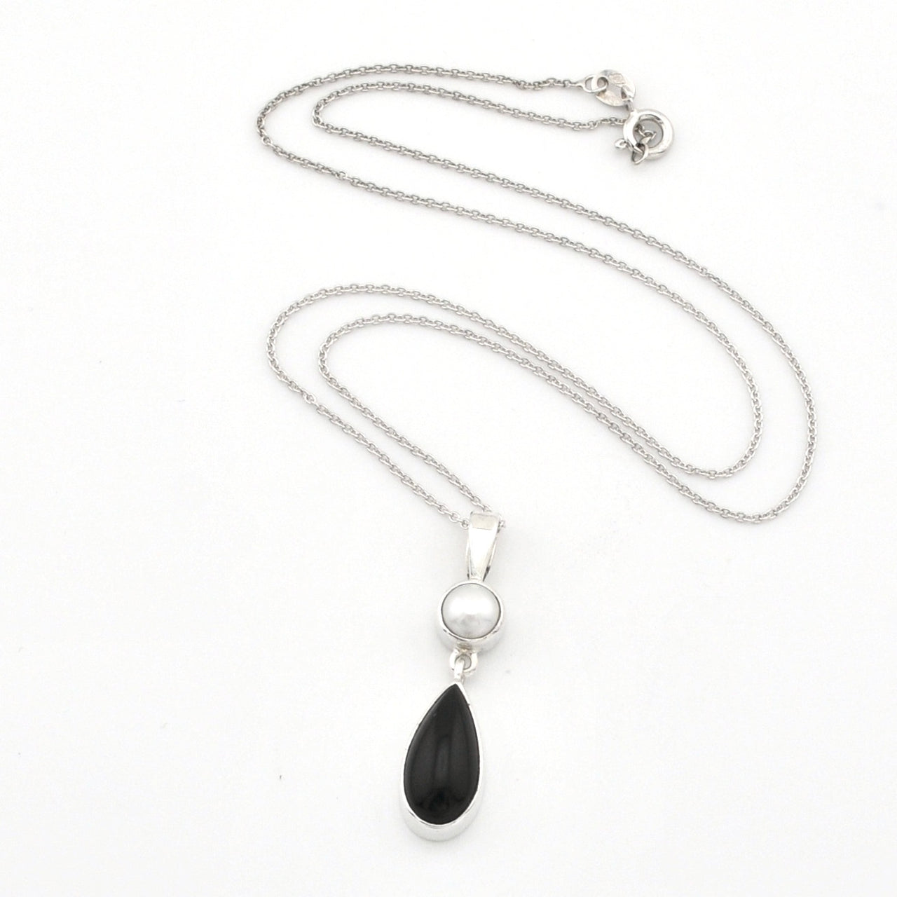 A silver necklace featuring a teardrop-shaped black onyx pendant and a small round white pearl, displayed on a clean white background.