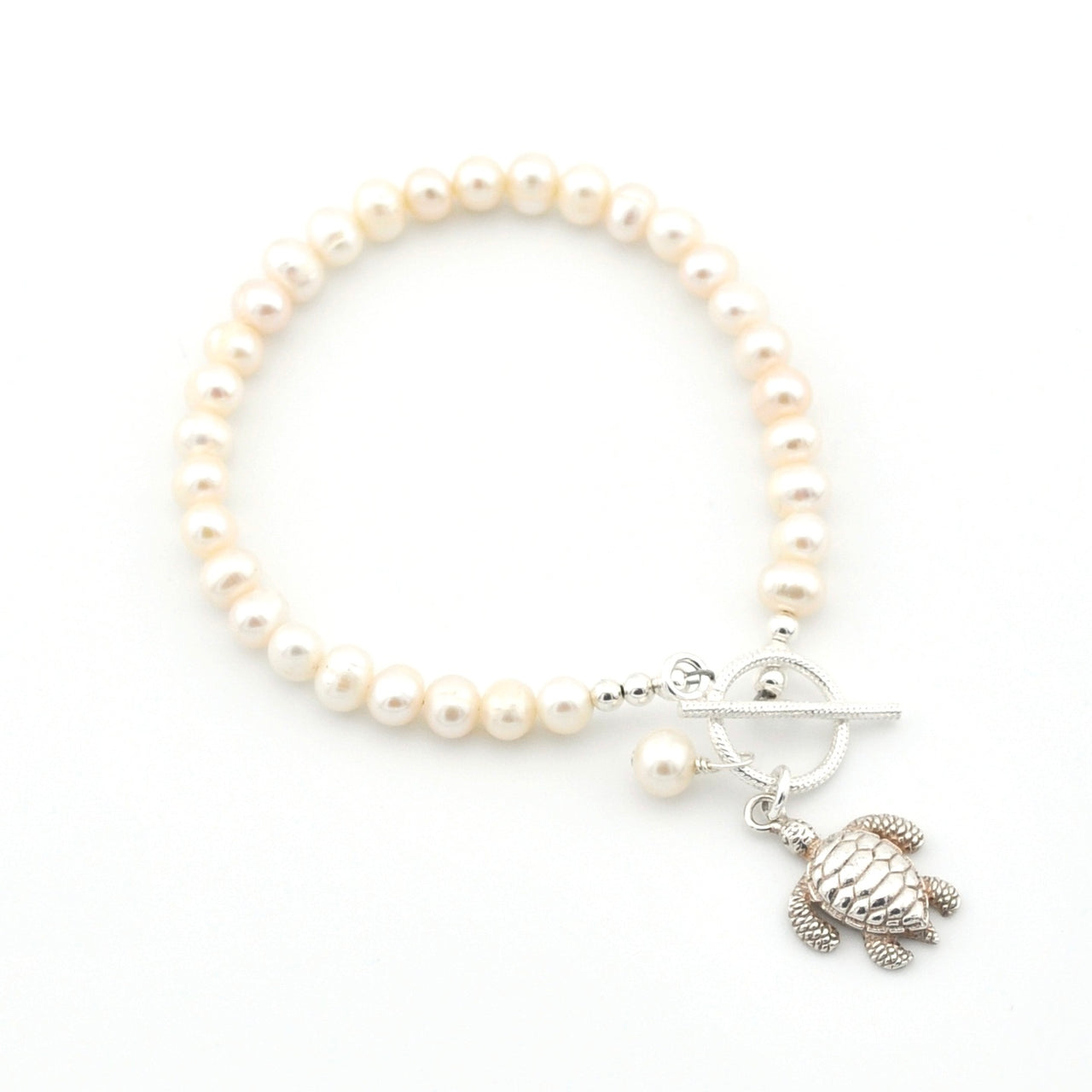 Pearl bracelet with a turtle charm on a white background