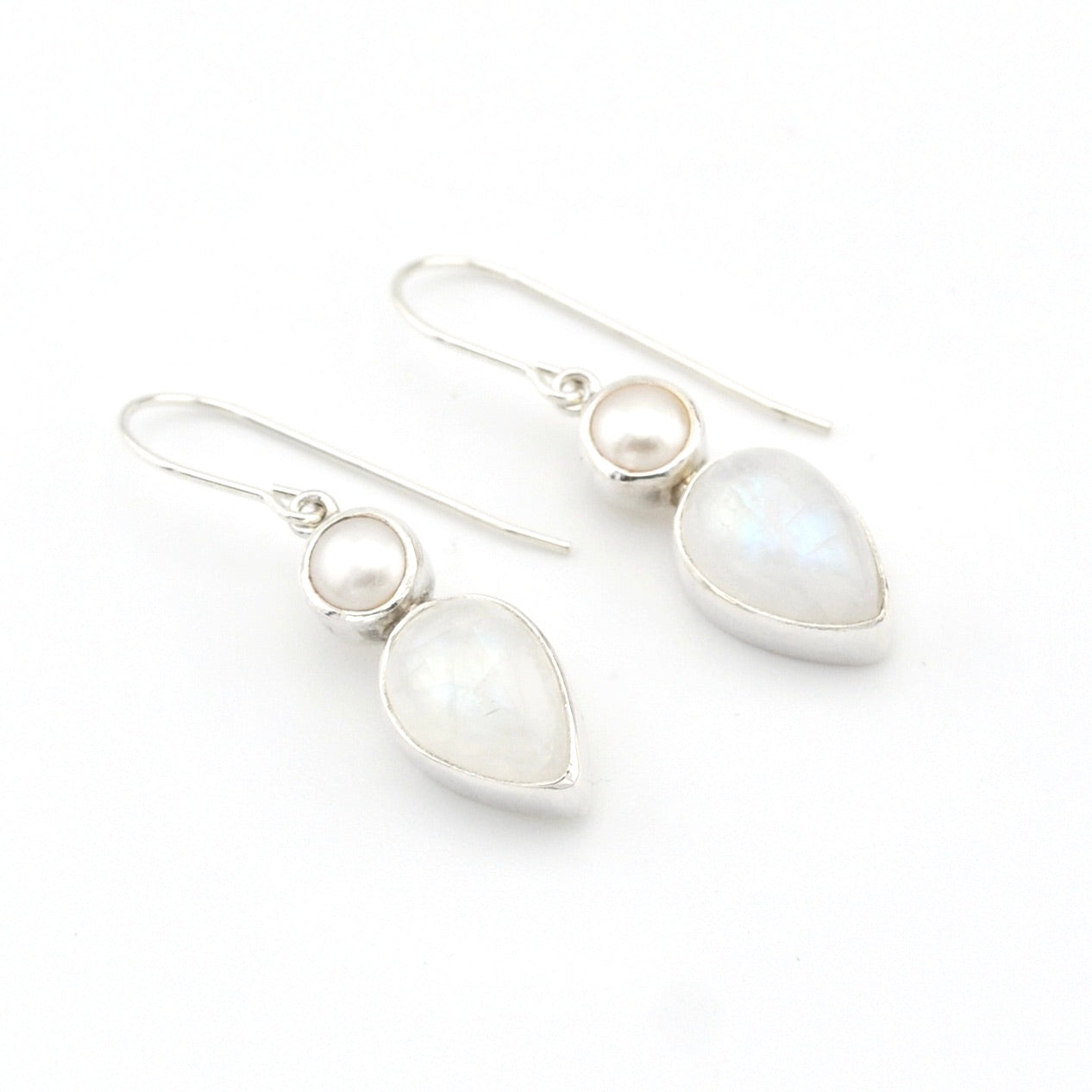 Pair of silver earrings with teardrop-shaped white stones on a white background