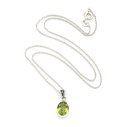 A silver chain necklace with an oval peridot pendant, displayed on a clean white background.