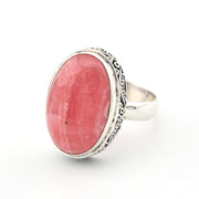 A silver ring featuring a large oval pinkish-red stone, set against a plain white background.