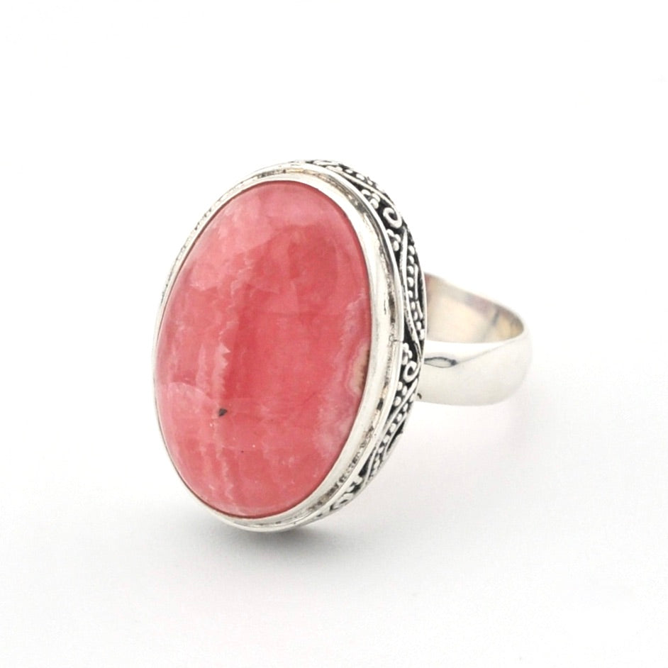 A silver ring featuring a large oval pinkish-red stone, set against a plain white background.