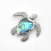 Tortoiseshell turtle brooch with abalone shell center on a white background