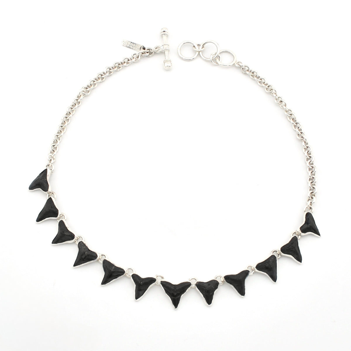 Silver necklace with 12 fossil shark teeth on white background.