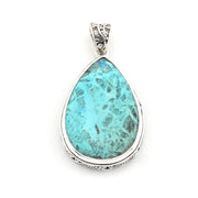 A teardrop-shaped turquoise pendant with a silver filigree border and bail, shown on a plain white background.