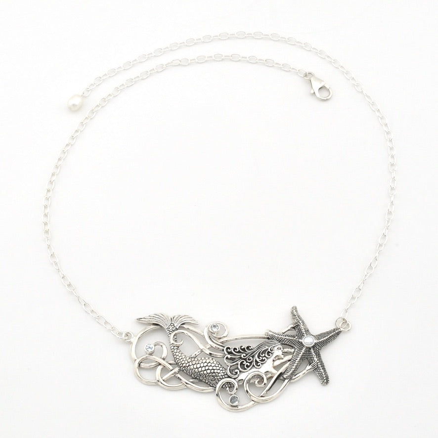 A silver-toned necklace featuring a mermaid tail and starfish pendant design, displayed on a clean white background.