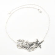 A silver-toned necklace featuring a mermaid tail and starfish pendant design, displayed on a clean white background.