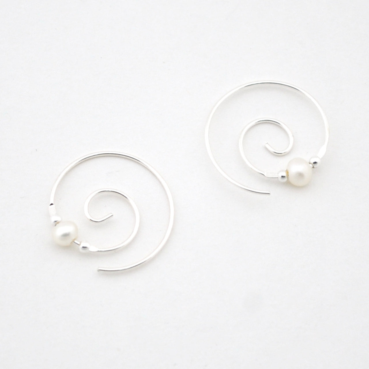 Silver spiral earrings with pearls on a white background