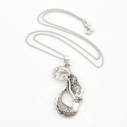 A silver pendant necklace featuring a detailed mermaid tail with textured scales and engraved patterns, displayed on a clean white background.