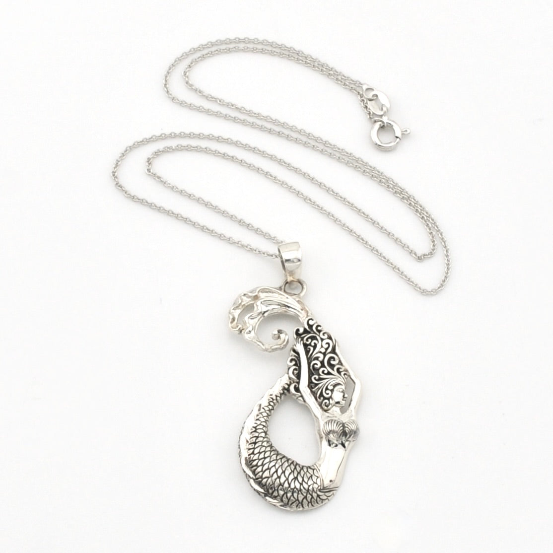 A silver pendant necklace featuring a detailed mermaid tail with textured scales and engraved patterns, displayed on a clean white background.