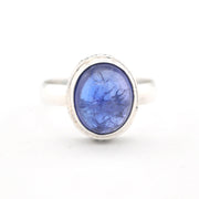 Silver ring with a blue stone on a white background
