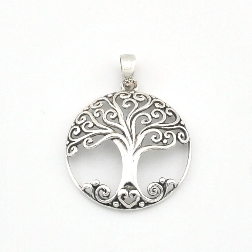 A silver tree of life pendant with intricate filigree cutouts and a heart-shaped base, shown on a plain white background.