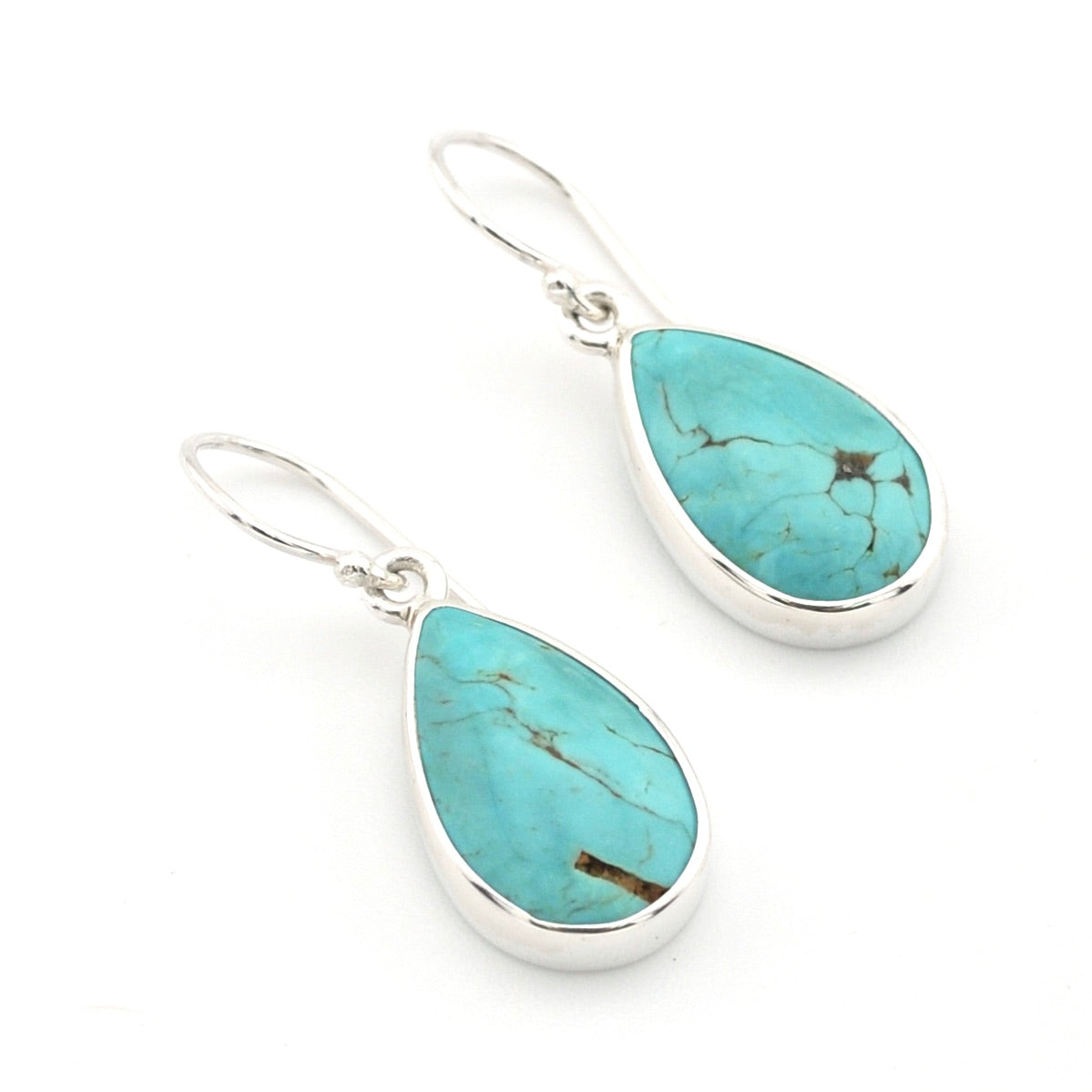 A pair of silver drop earrings featuring teardrop-shaped turquoise stones with natural matrix veining, set in polished silver bezels on a white background.