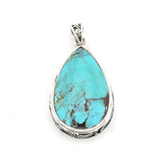 A teardrop-shaped turquoise pendant with a silver-toned ornate border and bail, shown on a plain white background.