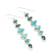A pair of sterling silver dangle earrings featuring a graduated sequence of oval and teardrop-shaped turquoise and green malachite stones, displayed on a clean white background.