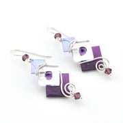Set of purple and silver earrings on a white background