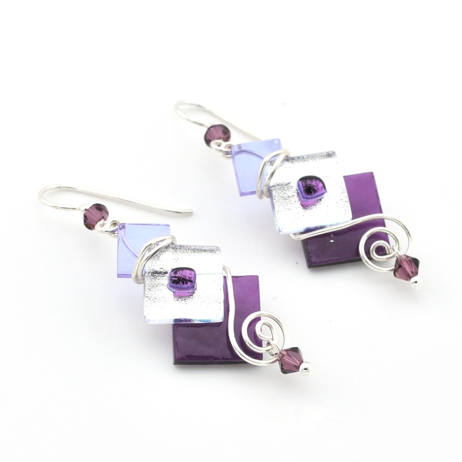 Set of purple and silver earrings on a white background