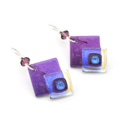 Purple square earrings with a central black circle on a white background