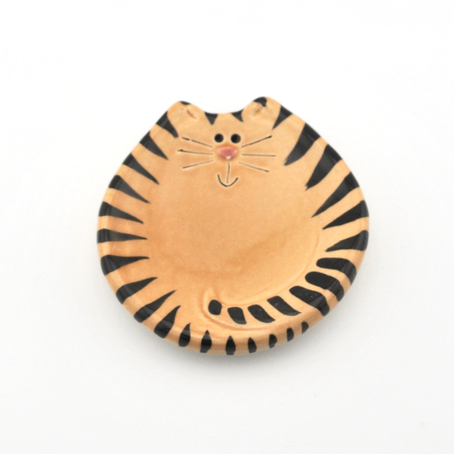 Ceramic dish shaped like a tiger with black stripes on a white background