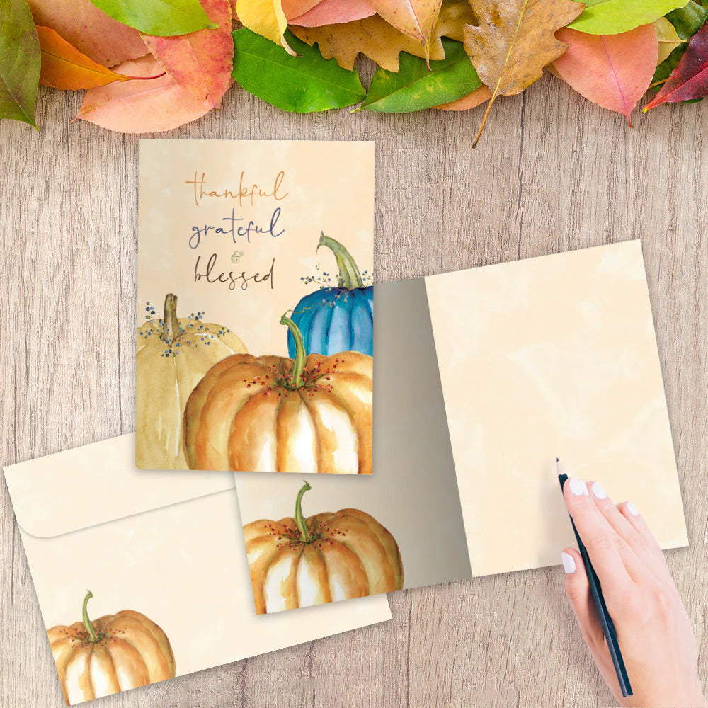 Autumn-themed greeting card with pumpkins and leaves on a wooden surface.