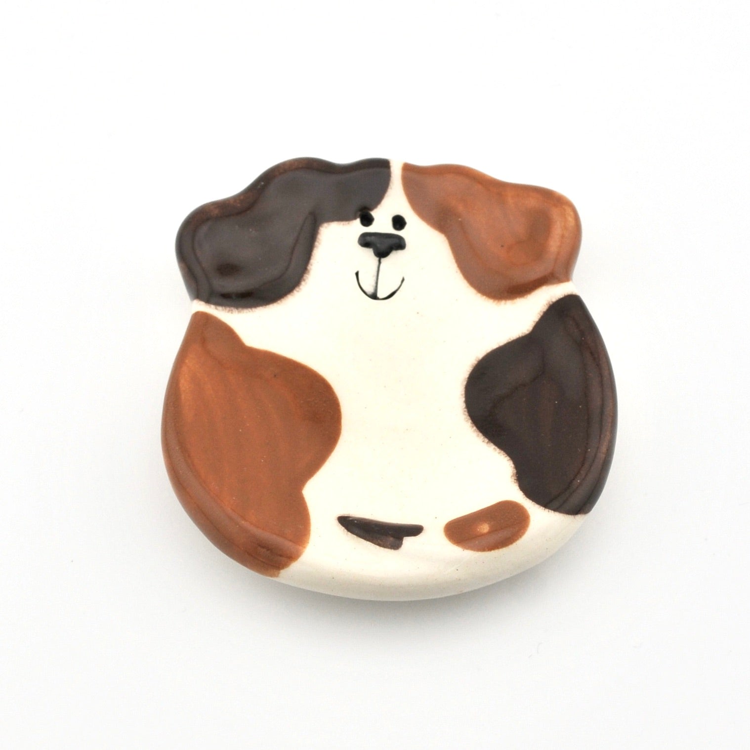 Dog-shaped dish with brown and black markings on a white background