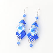 Blue glass earrings with silver swirl designs on a white background